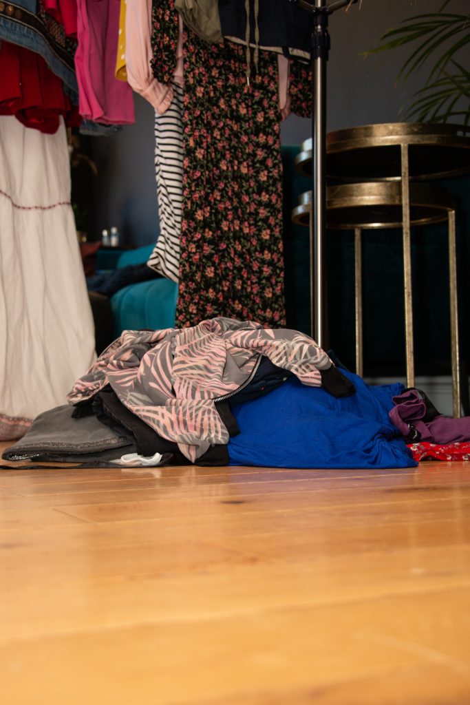 A pile of unwanted clothes on a wooden floor